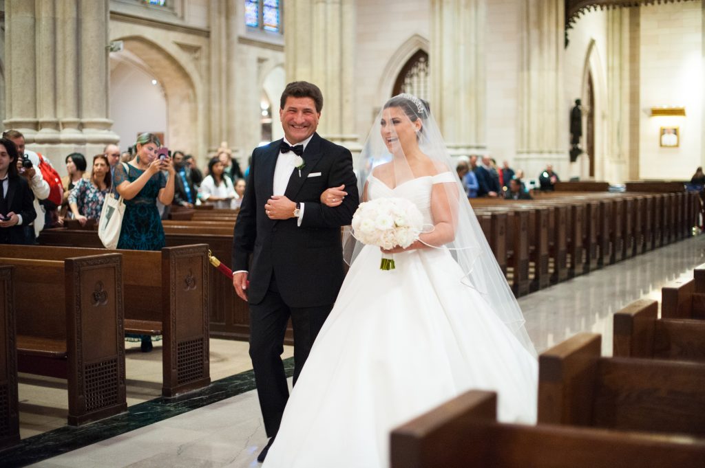 bride and father walking down aisle smiling