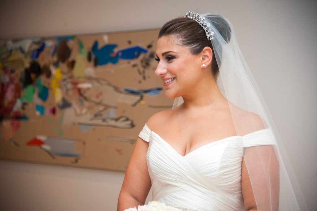 bride in makeup and gown, profile shot in front of painting