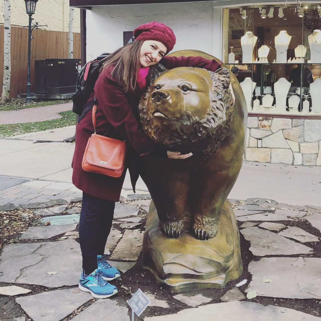 Sharon Becker, makeup artist, outside hugging a bear statue