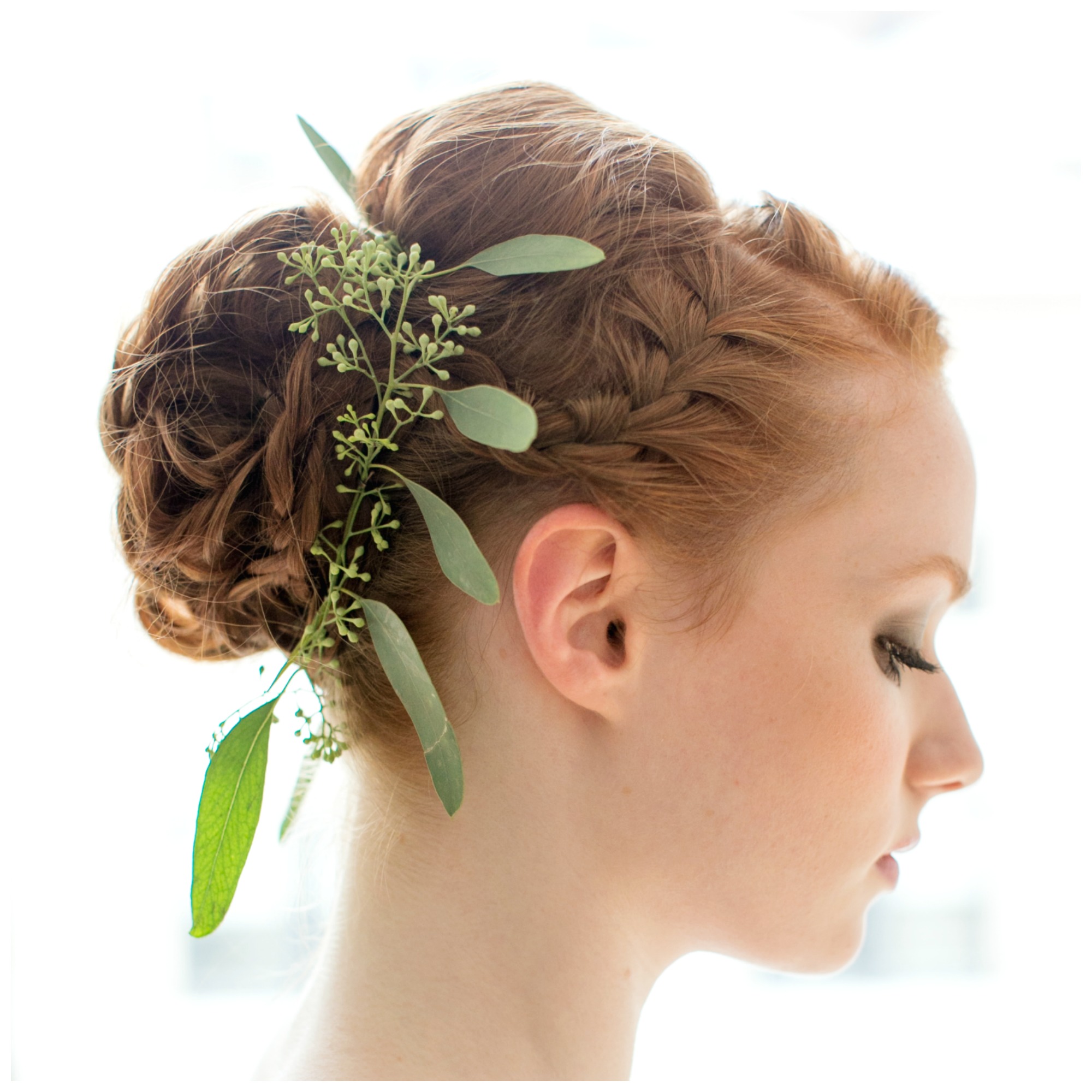 Bride with red hair knotted into braided bun, decorated with leaves