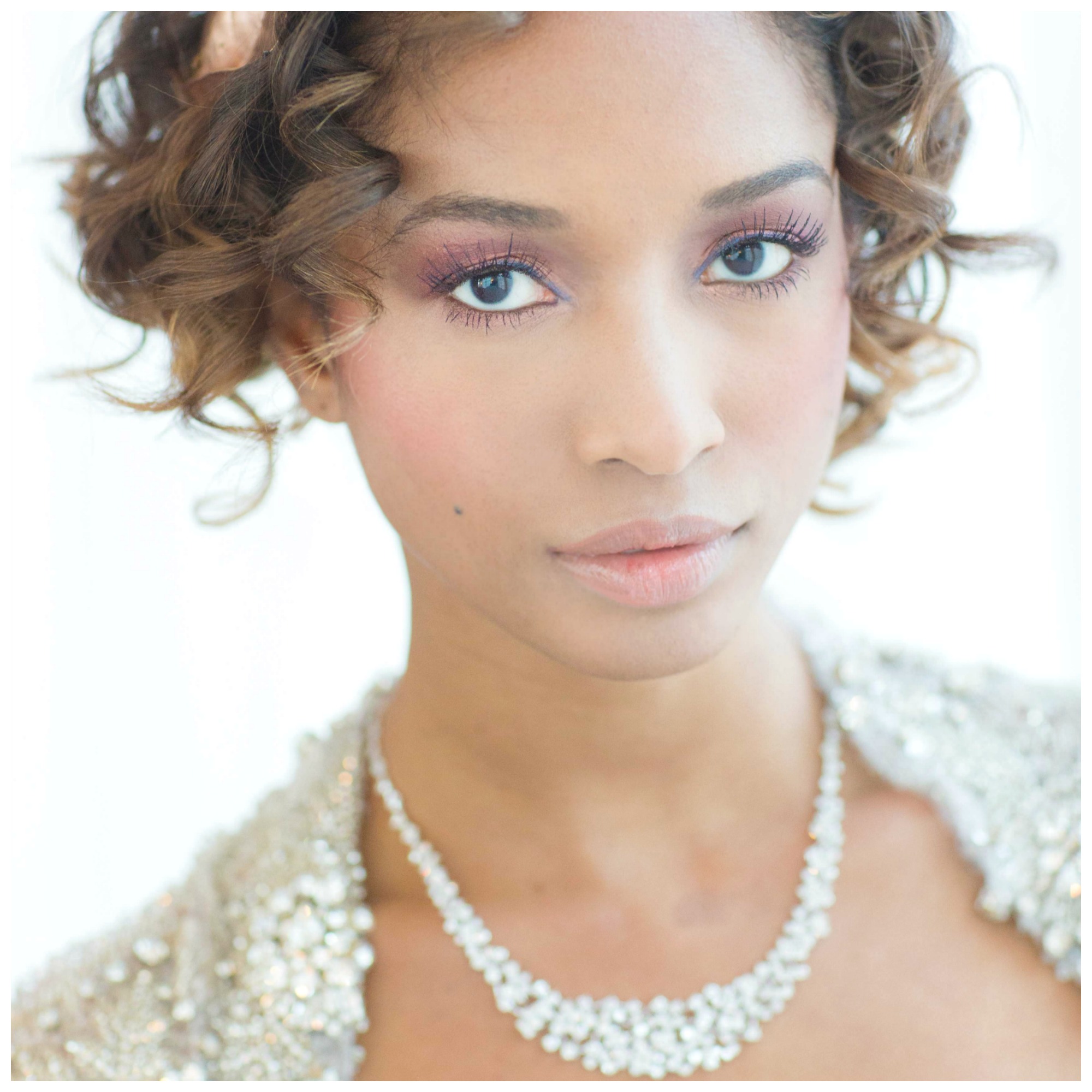 Bride in sparkling wedding gown, diamond necklace, and soft romantic makeup
