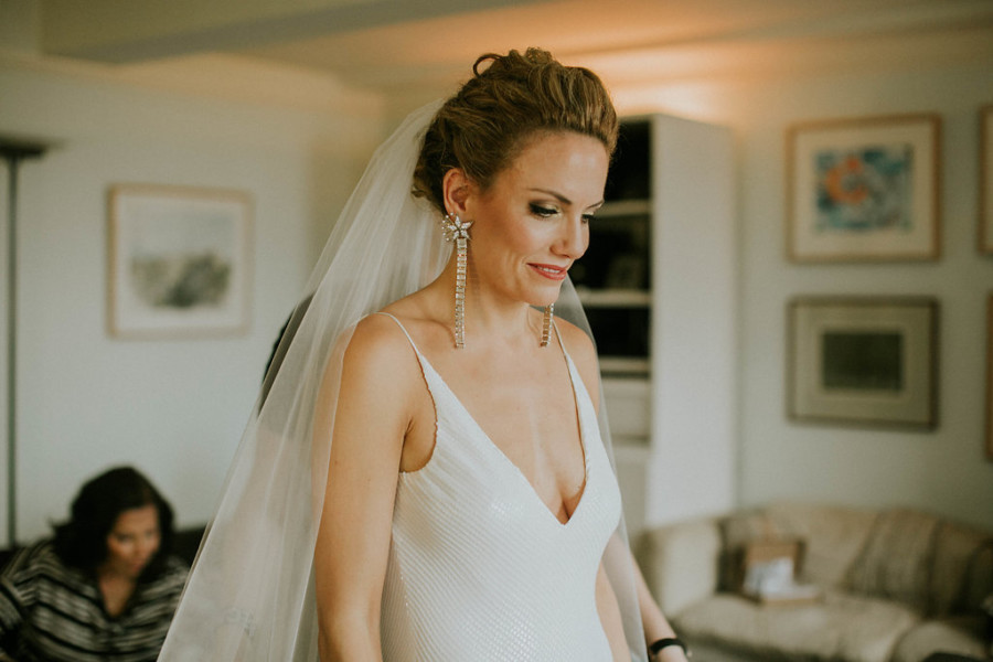 Bride with natural curls swept into romantic chignon with disco glam makeup and long earrings, in Brooklyn Heights, New York