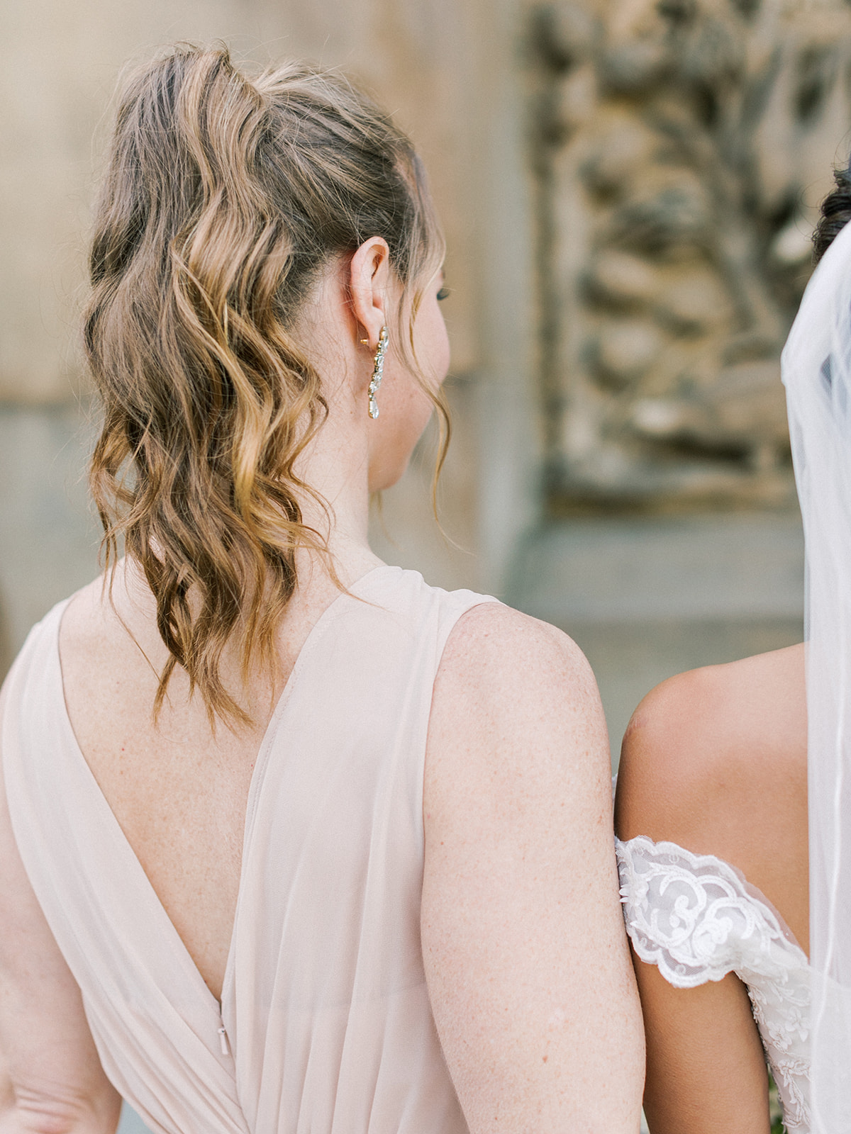 Bridesmaid with light brown hair with highlights styled in high wavy modern ponytail