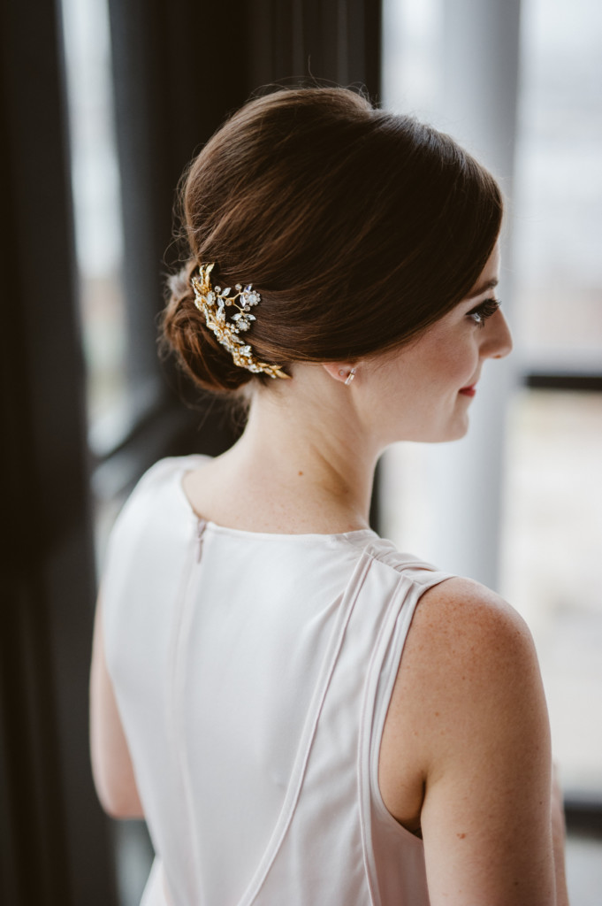 Bride with auburn hair styled into modern classic chignon with modern hair accessory, pictured at the Wythe Hotel in Williamsburg, Brooklyn