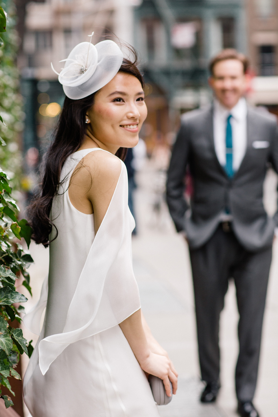 Bride in chic day white day dress with little white hat poses on New York City street