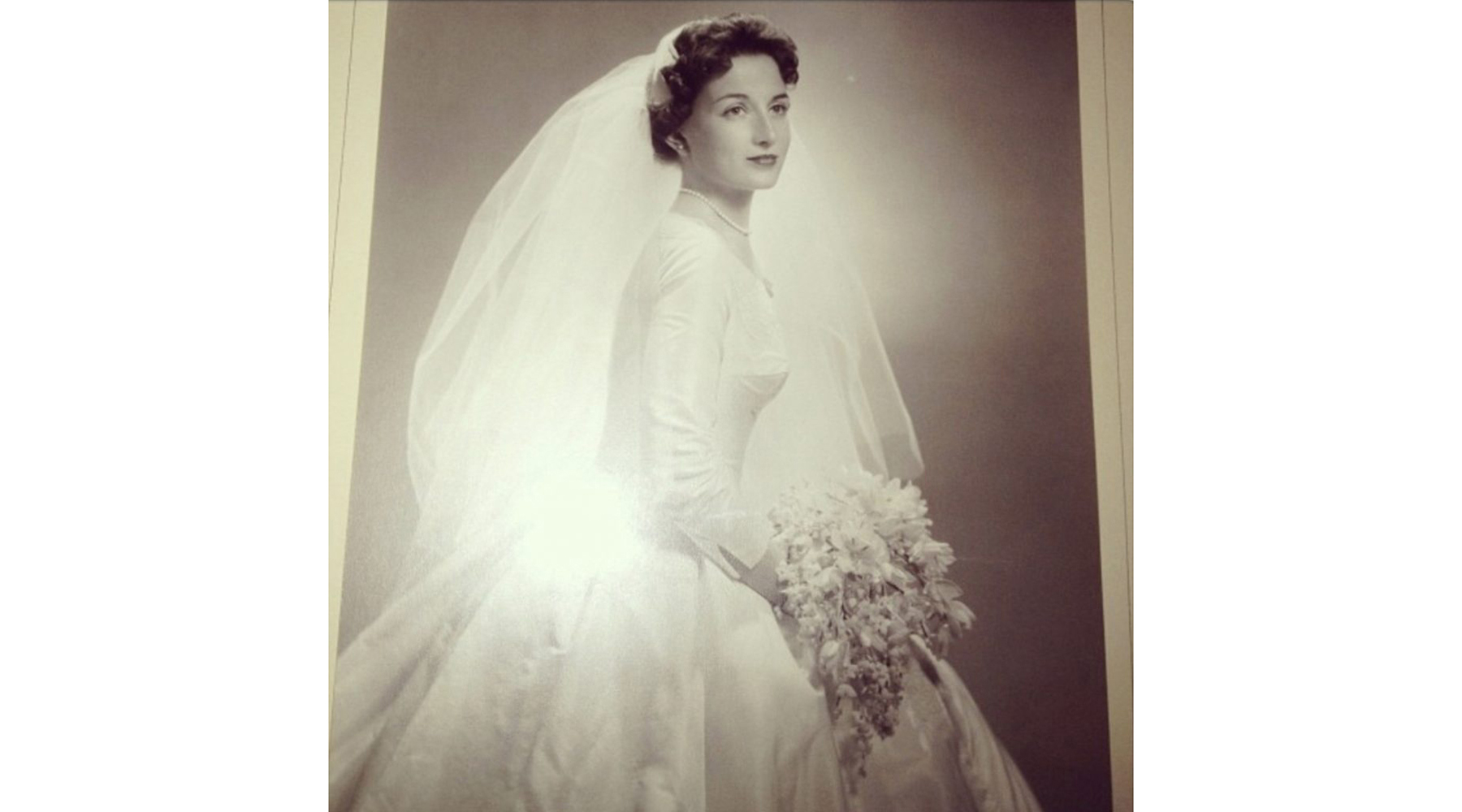 Black and white bridal portrait, Sharon's mother with wavy dark hair, 3/4 angle. Long veil, full skirt, big bouquet.